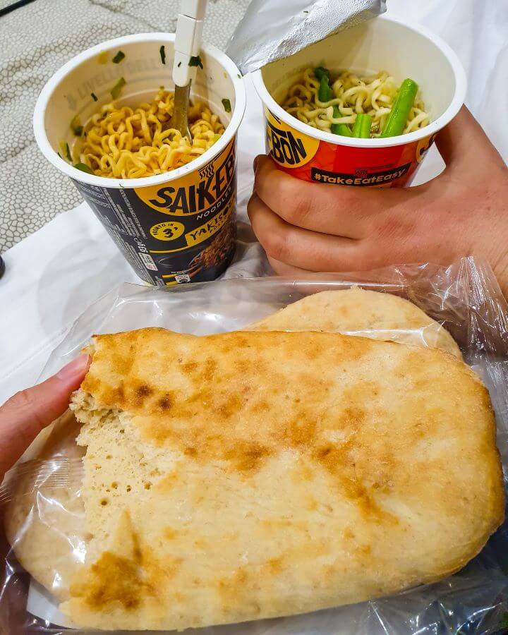 Two noodle cups with veggies in them and 2 pieces of naan. A very budget meal! "Creating a Realistic Travel Budget: What You Need to Consider"