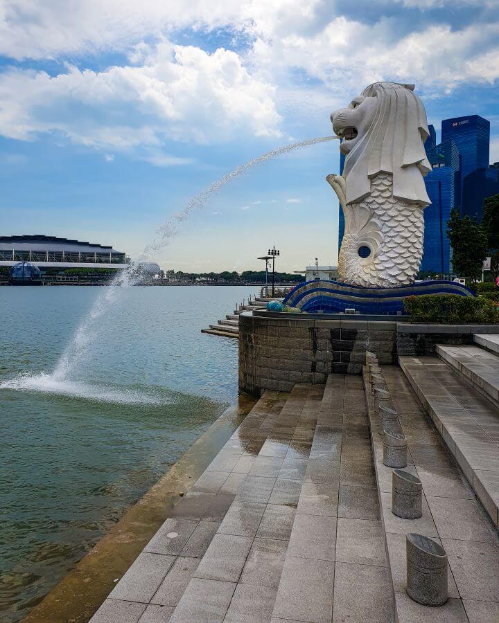 The Merlion statue on the Singapore River with a jet of water shooting from its mouth into the river below. 