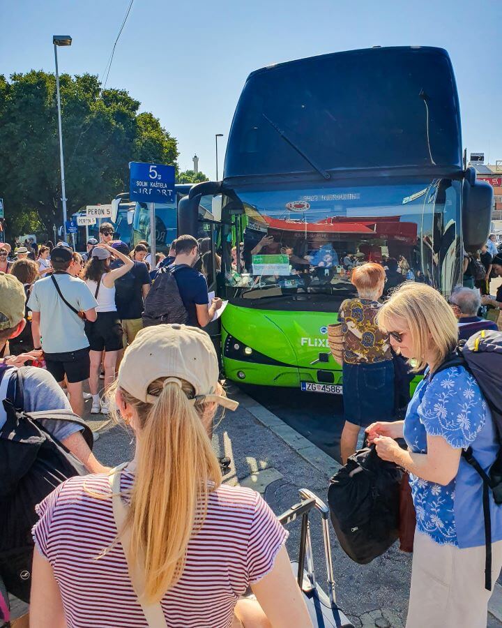 A big double decker FlixBus parked in a bay with people crowding around the outside of it "FlixBus: The Best Budget Way to Travel Europe Easily"