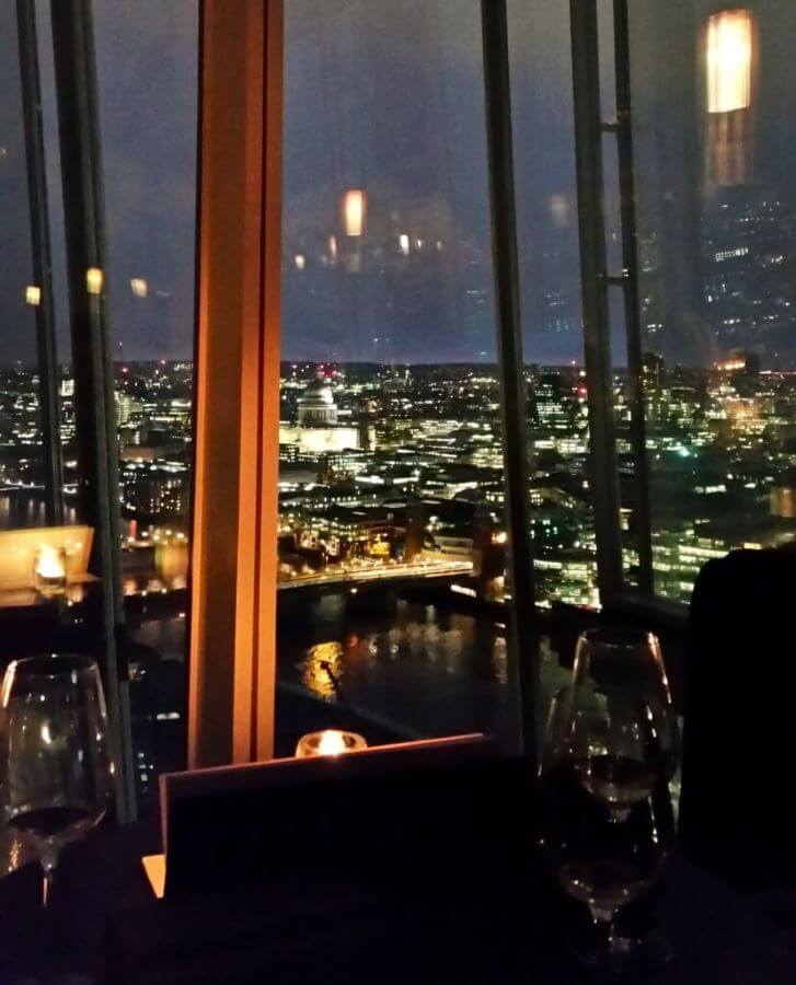 A view over London, England all lit up at night taken through the glass of the GÔNG bar in The Shard "Three Great Hacks To Save Money In London"