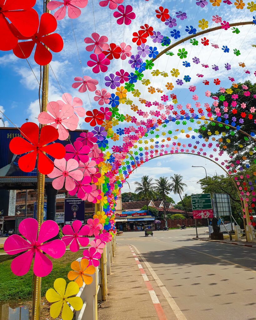 A picture of a bridge in Siem Reap Cambodia with heaps of fake colourful flowers over the bridge "The Ultimate Guide to Siem Reap: Temples, Markets, and More!"