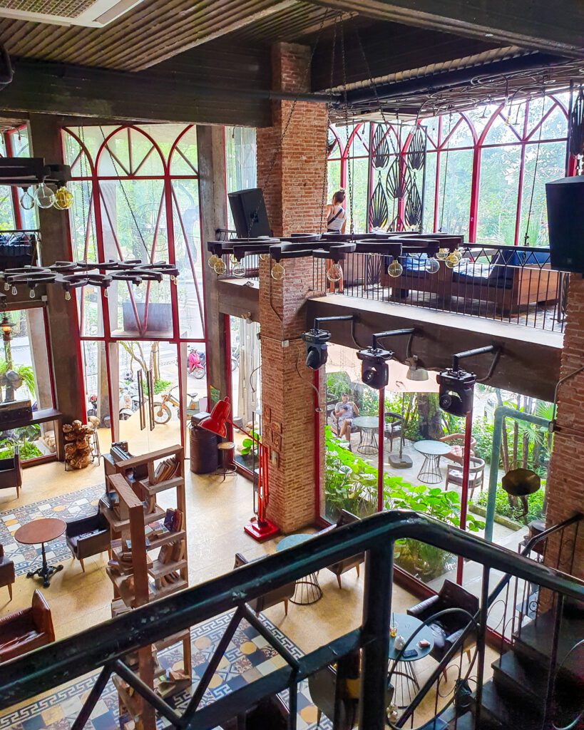 Inside Temple Coffee n Bakery in Siem Reap Cambodia which is a double level cafe with rugs, books and chairs on the bottom level. It is a very cosy and inviting looking space "The Ultimate Guide to Siem Reap: Temples, Markets, and More!"