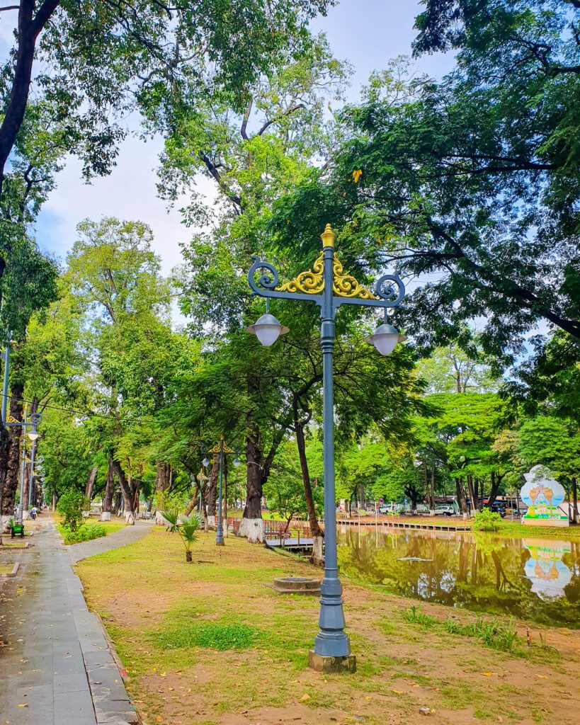 The Siem Reap River in Cambodia with trees all around it and a path going alongside it with beautiful blue lampposts along the path "The Ultimate Guide to Siem Reap: Temples, Markets, and More!"