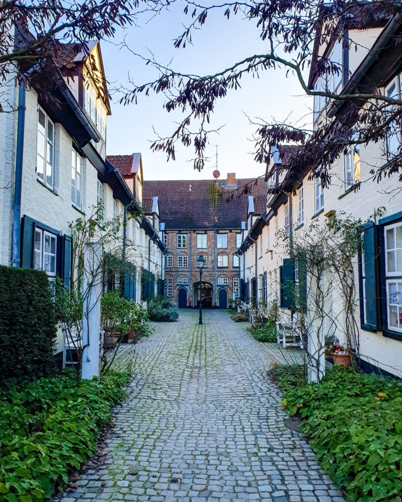 The Glandorps Hof courtyard in Lübeck, Germany. The courtyard is small and has old buildings and a cobbled street with a light post in the middle "How to See Lübeck in a Day Trip from Hamburg"