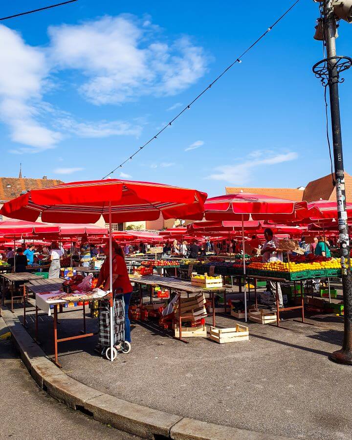 Lots of red umbrellas with tables underneath full of fresh produce at the Dolac Market in Zagreb, Croatia "How to Affordably See Zagreb"