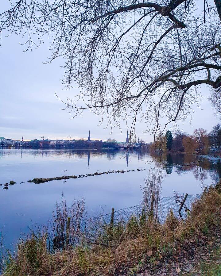 A view of Außenalster or the Outer Alster Lake in Hamburg, Germany with some beautiful European buildings around it "How to See Hamburg on a Budget"