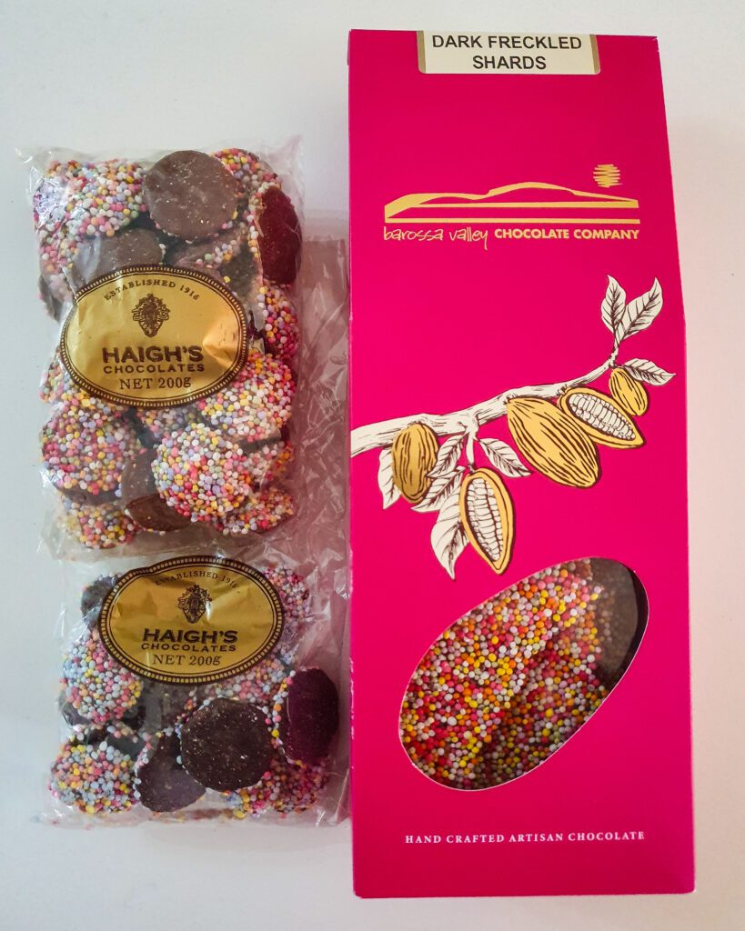 A picture of two packets of Haigh's chocolate freckles and a pink box with some freckle shards from the Barossa Valley chocolate company in Adelaide, SA "How to See the Best of Adelaide in a Weekend"