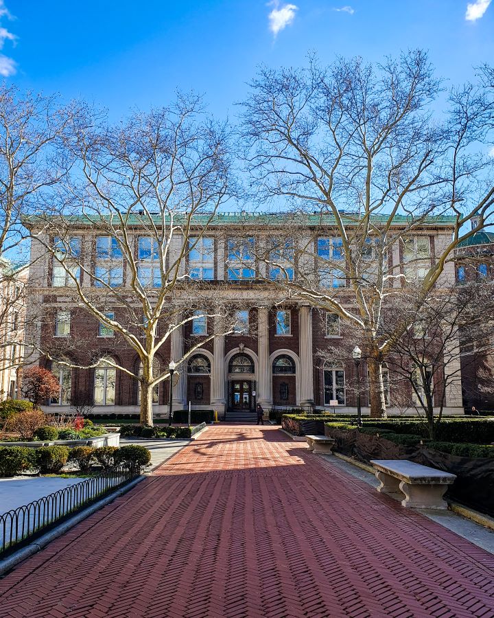 A red brick path leading up to a big maroon and white building on the Columbia University campus in New York City, USA. There are trees around the building and bushes along the path leading up to it "Non-Touristy Activities for Return Visitors to New York City"